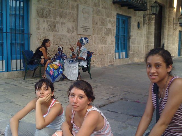 UN DESCANSITO EN LA PLAZA LA CATEDRAL Y DE FONDO UNA SANTERA TÍPICA DE LA HABANA